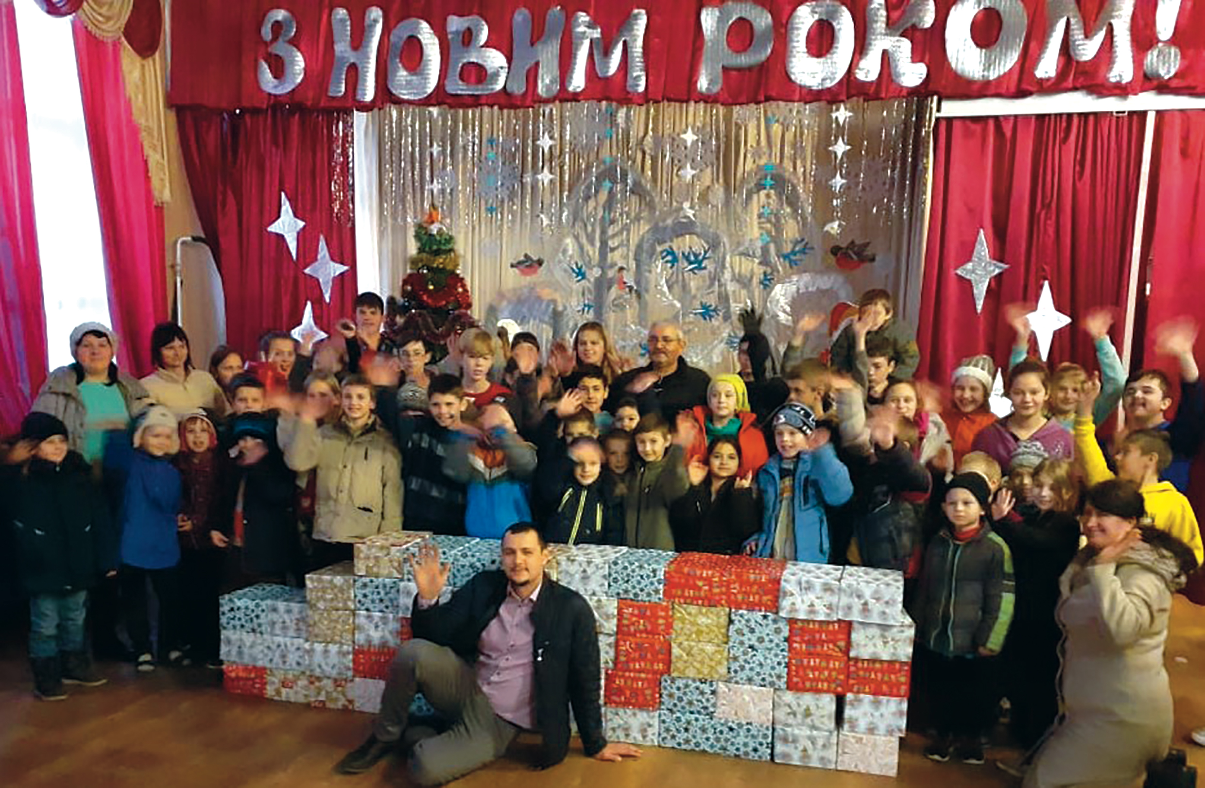 Children standing behind a stack of presents.